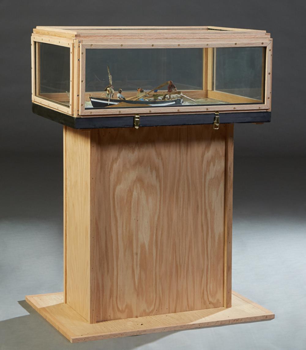 Wood-framed diorama display case on a stand, with a small ship model visible inside behind glass panes.