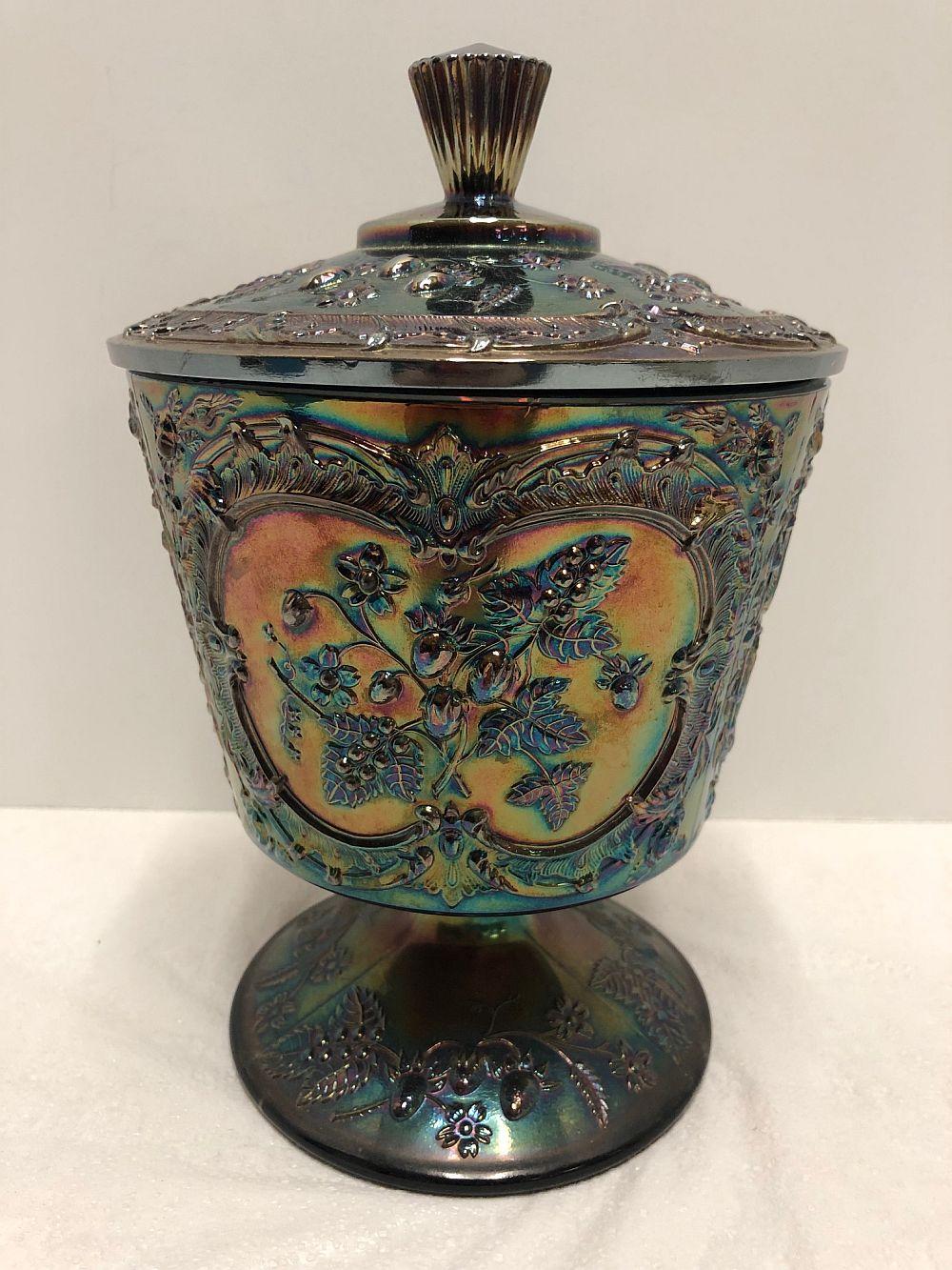 Iridescent glass covered candy dish with a fluted knob lid and embossed floral designs in blue, green, and amber.