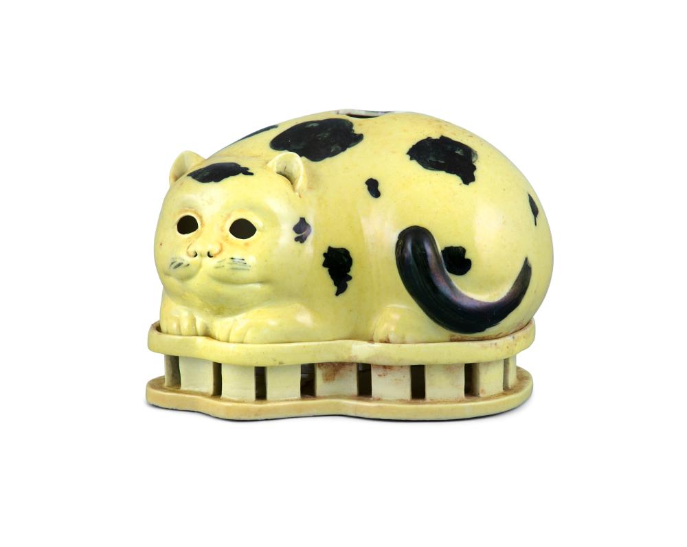 *A RARE CHINESE EXPORT PORCELAIN CAT NIGHT LIGHT AND STAND China, Qing Dynasty, 18th to 19th century Made in two parts, the cat itself and the openworked stand, of black and yellow enamelled porcelain. The lovely cat is depicted recumbent while asl sold by Adam's, lot 110A — auction record photograph