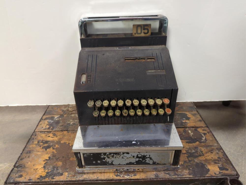 Vintage black cash register with a row of numbered coin/price dials and a clear top window marked “.05”.