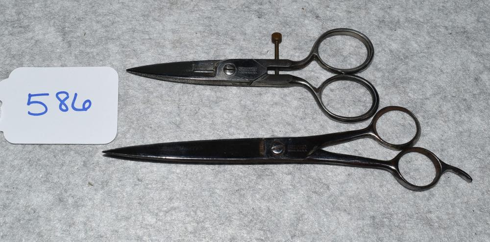 Pair of vintage metal scissors laid on a gray textured surface, showing finger rings and pointed blades.