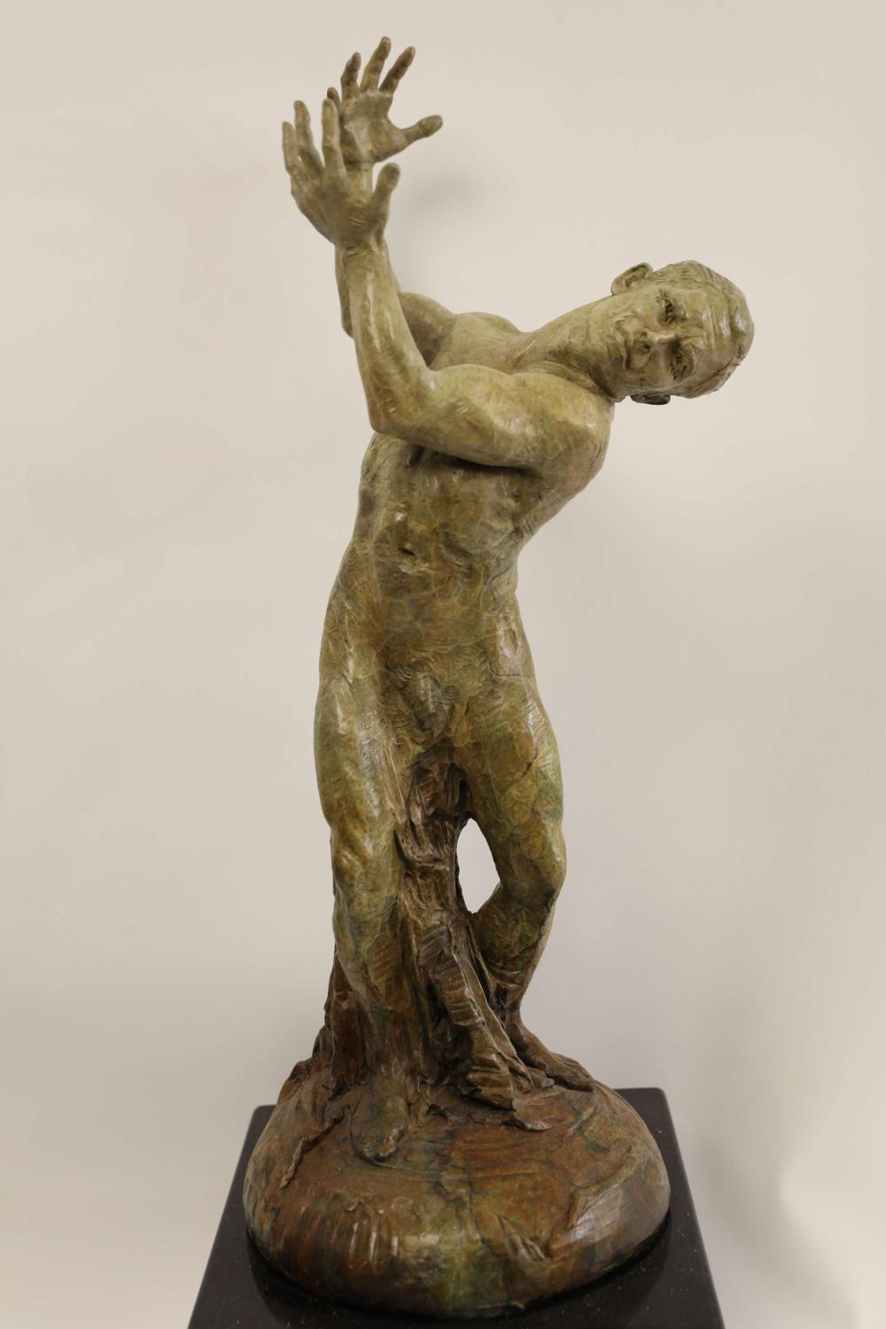 Bronze sculpture of a human figure kneeling with one leg bent and both hands raised, head resting forward on the outstretched arms.