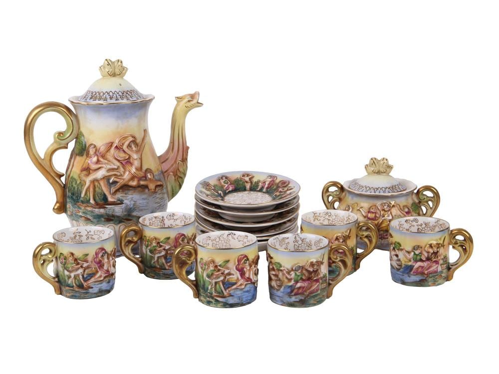 Vintage decorative porcelain Greek-themed tea set with a lidded teapot, sugar bowl, creamers, and stacked saucers and cups, painted with figures and gold trim.