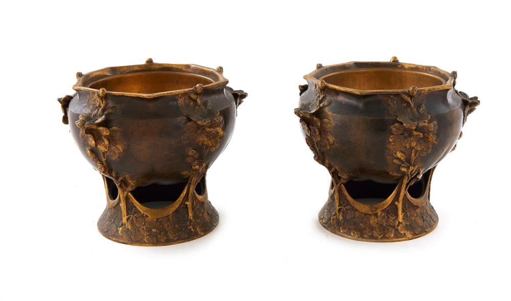 Pair of bronze cachepots with two side handles and leaf and floral relief decoration, shown against a white background.
