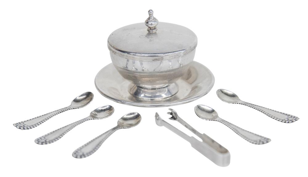 Round metal salt cellar with domed lid and knob, shown with six small spoons on a matching base.