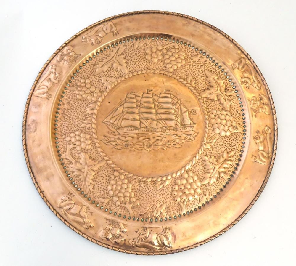 Frans Deutmann comparable auction result: a large arts crafts copper charger with embossed decoration depicting a ship at sea bordered by fr