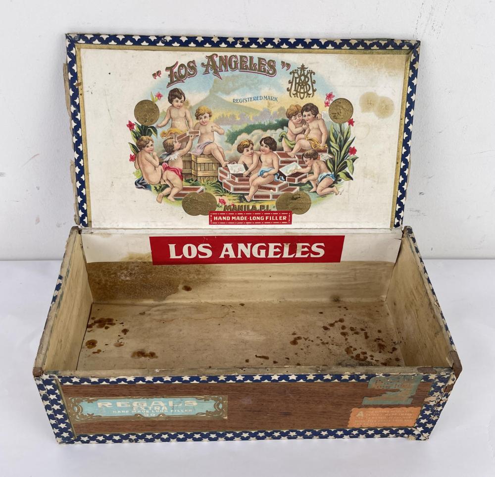 Open vintage cigar box with “LOS ANGELES” branding, blue star trim, and a vintage illustration of cherubs on the inside lid.