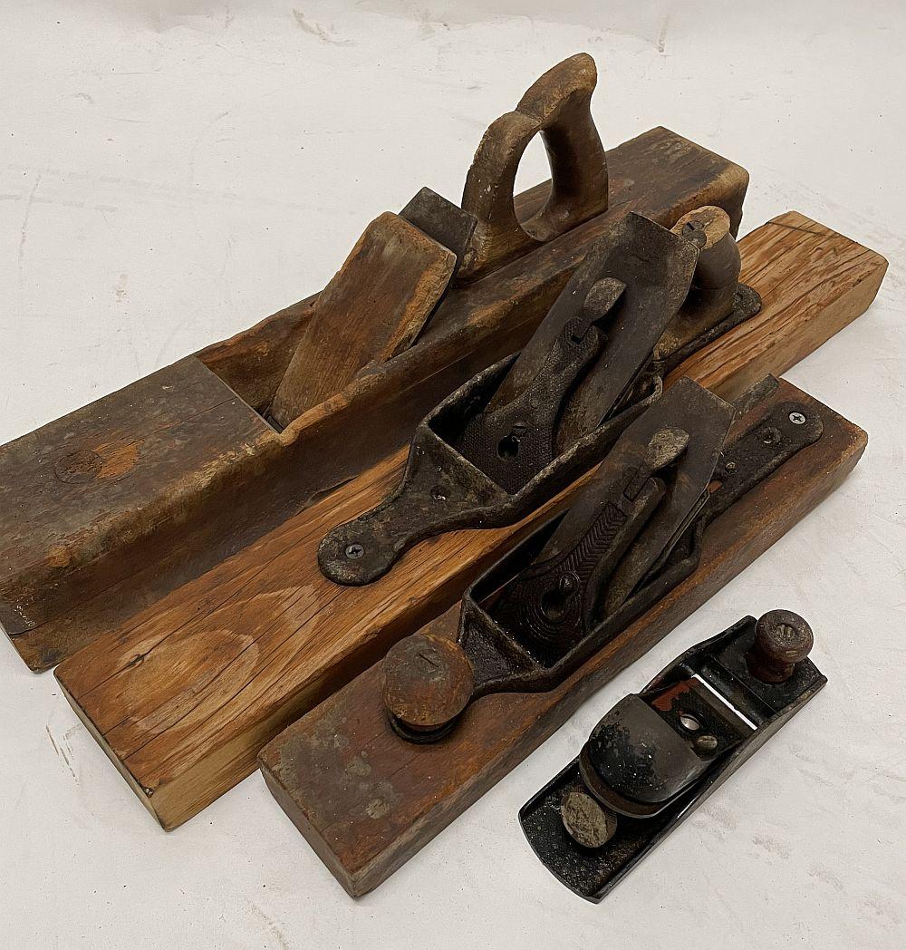 Set of vintage woodworking hand planes with wooden bodies and metal blades, shown on a white background.