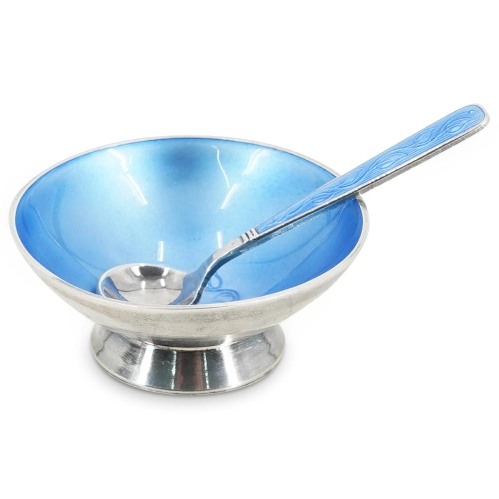 Silver salt cellar with a blue enamel-lined interior bowl and a matching spoon-like handle.