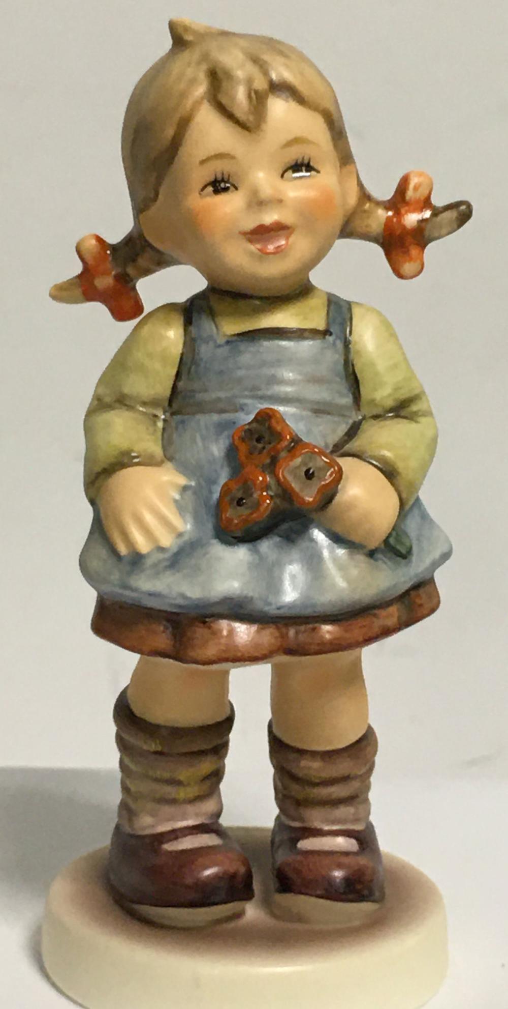 Small painted figurine of a child holding a bouquet of red flowers, wearing blue overalls and striped brown boots.