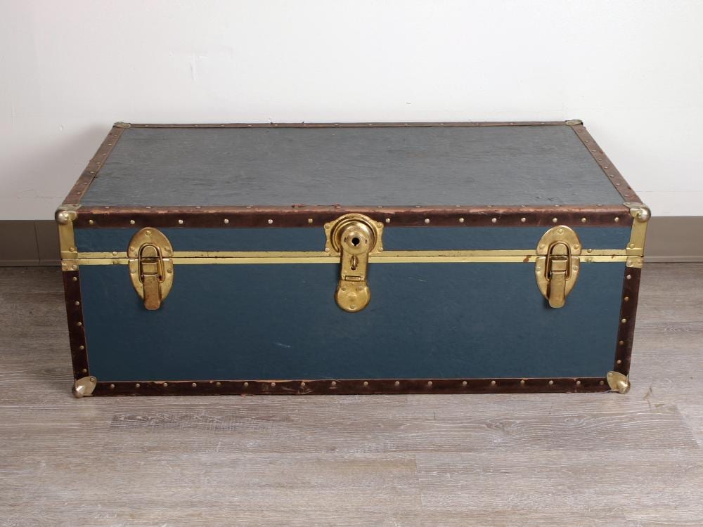 Vintage style metal trunk with blue and brown panels, brass corner caps, rivets, and three brass locks on the front.