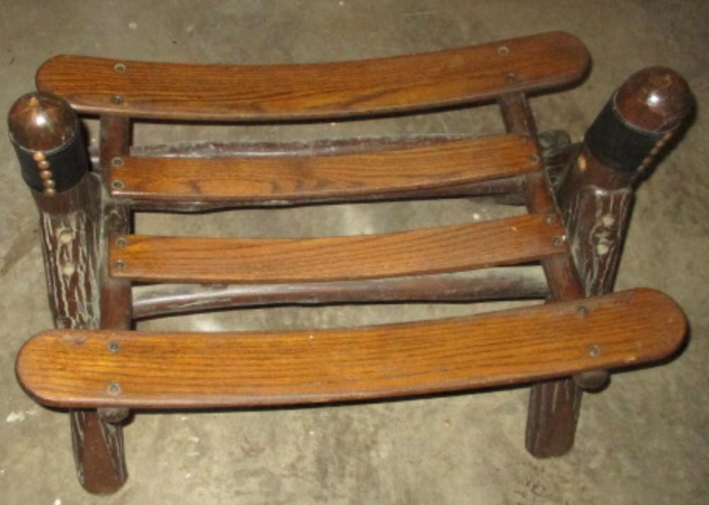 Wooden ottoman or foot stool with curved arms and carved posts, shown from above against a concrete floor.