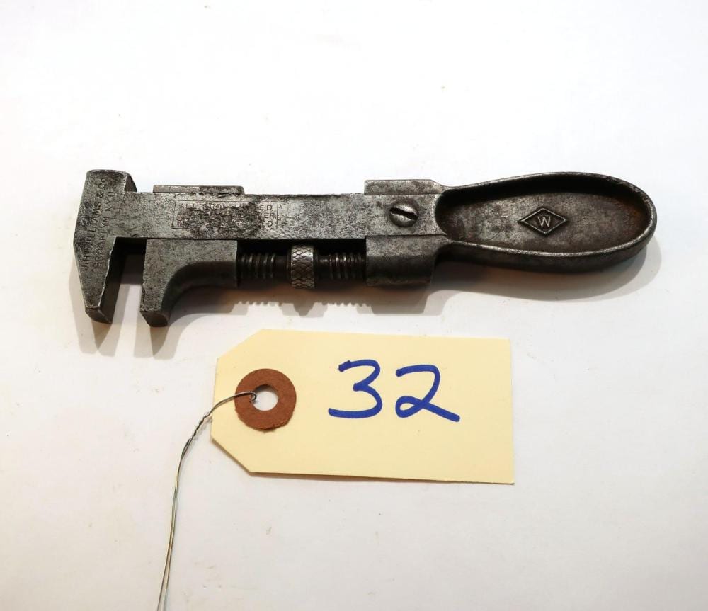 Metal bicycle nut wrench with an oval handle and stamped marks, shown on a white background with a paper tag labeled “32.”
