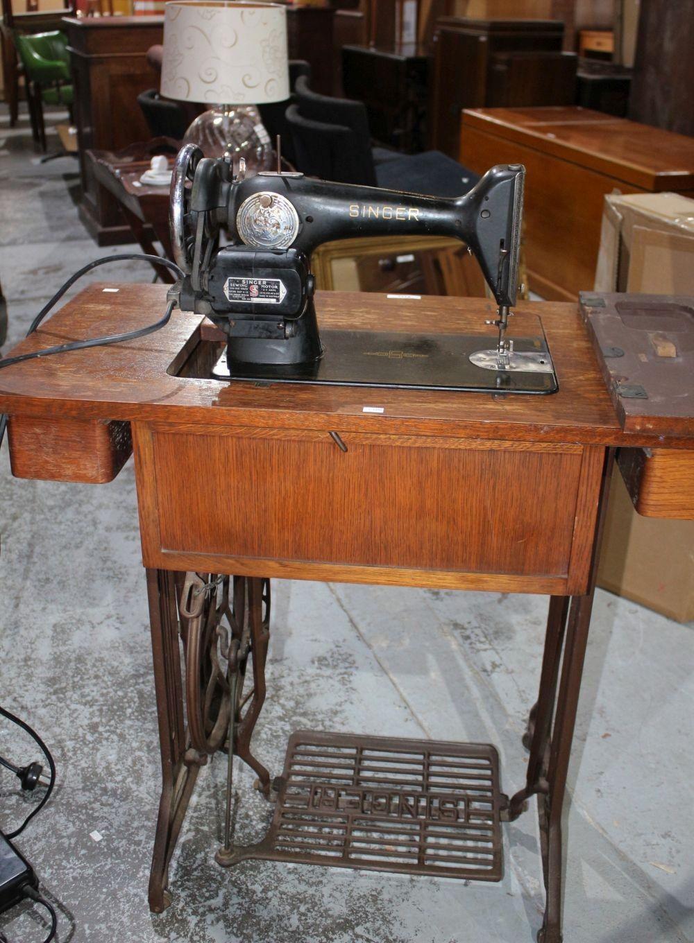 Vintage Singer Sewing Machine Table - oak top fitted with 2 drawers, cast iron treadle base with brown painted finish, fitted with an electric Singer Sewing Machine Model EE497989. 74cm high x 87cm wide x 42cm deep sold by Bargain Hunt Auctions, lot 2233 — auction record photograph