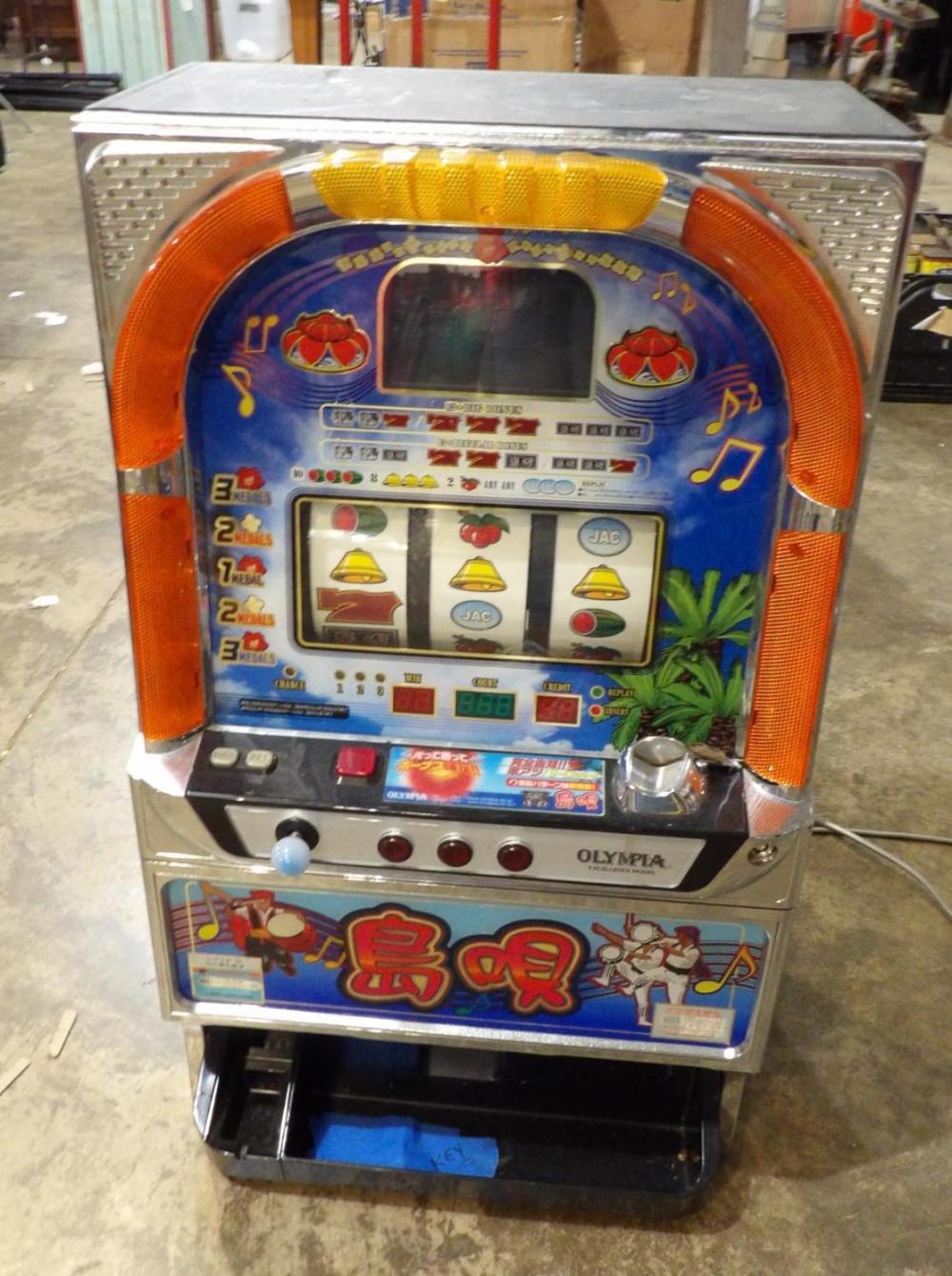 Front view of a vintage Olympia slot machine with illuminated marquee, three bell icons on a blue screen, orange side panels, and a key slot area.
