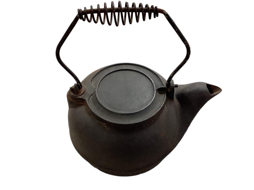 Small cast iron tea kettle with dark brown finish, round lid, spout, and arched handle.