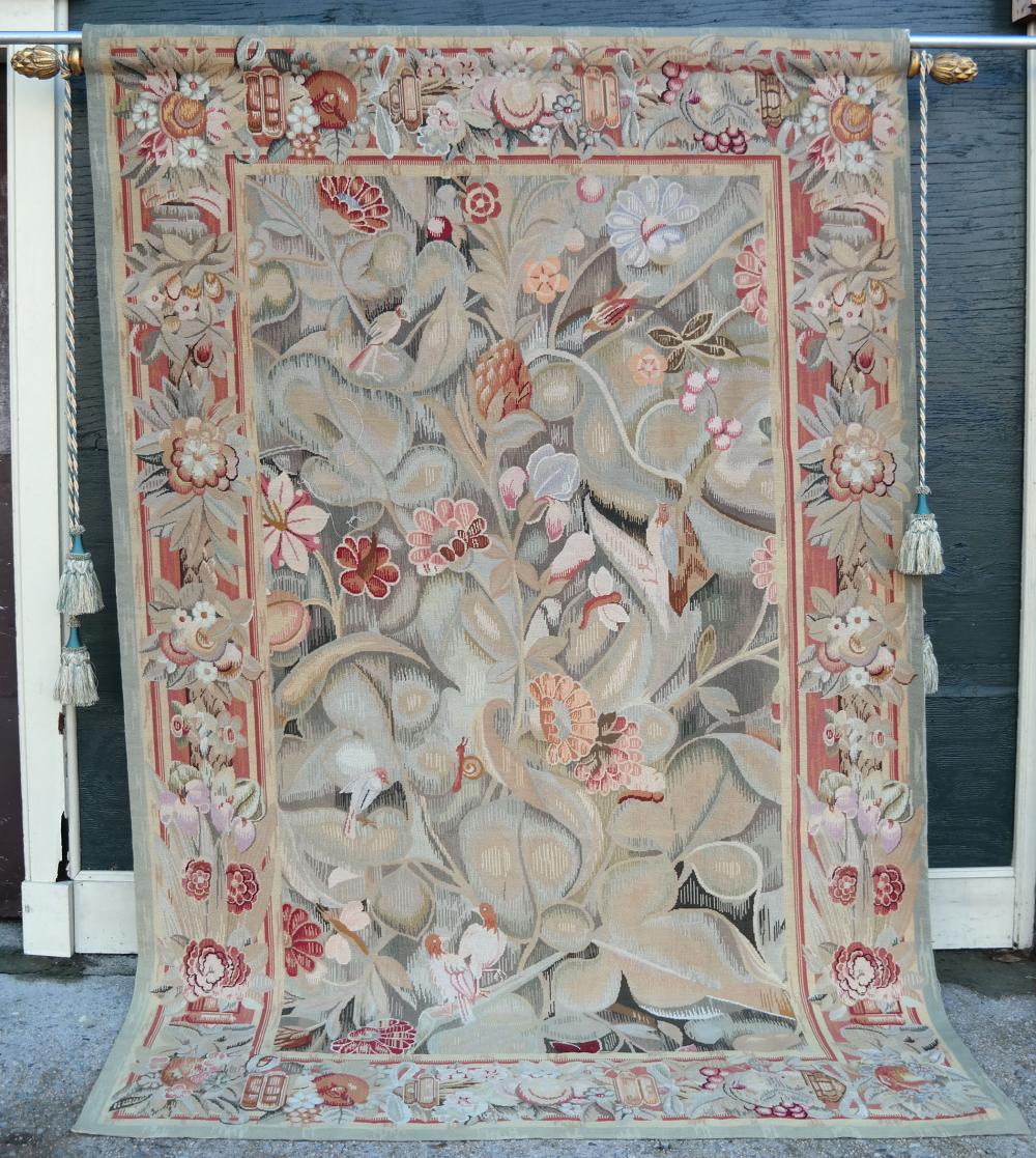Needlepoint tapestry on a rod featuring a central bird-and-flower pattern with red and pink accents and tassels at both sides.