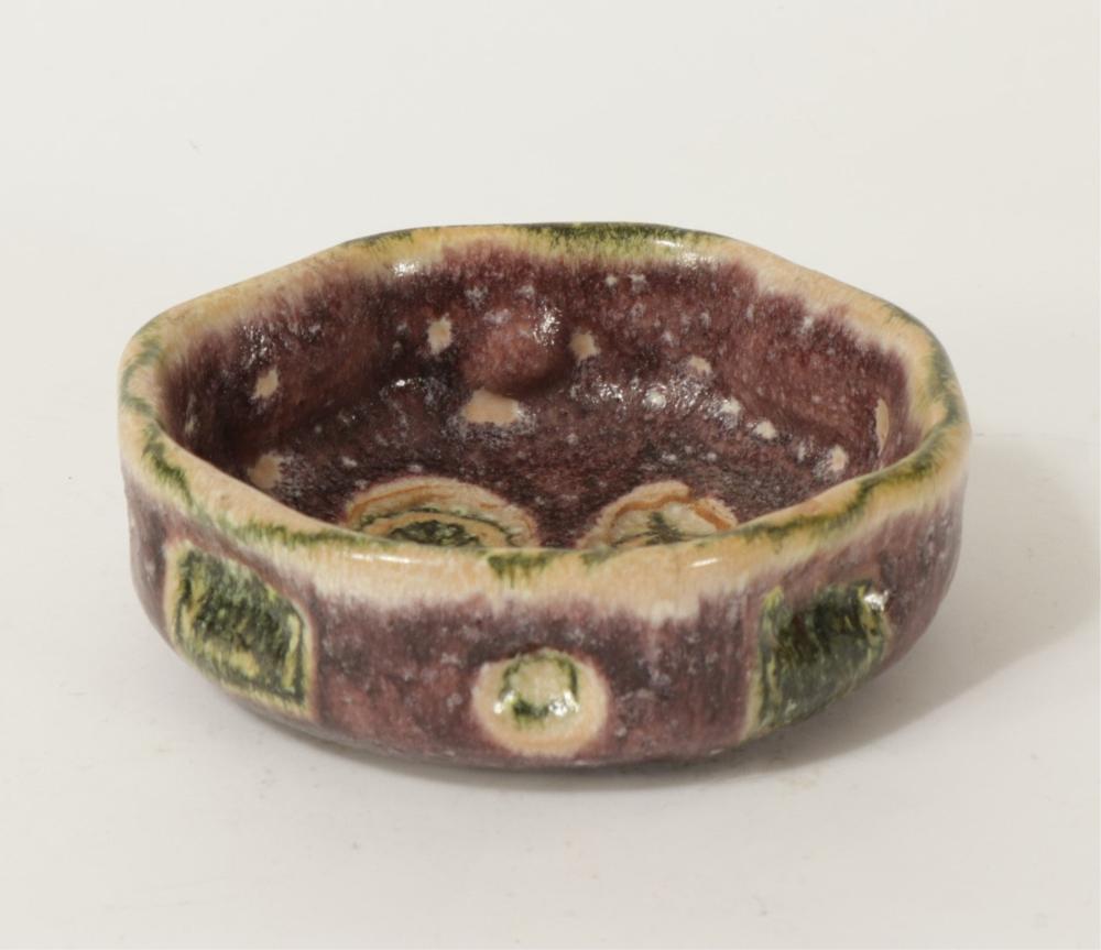 Glazed ceramic bowl with a speckled brown interior and green and yellow accents on the rim and outer sides.