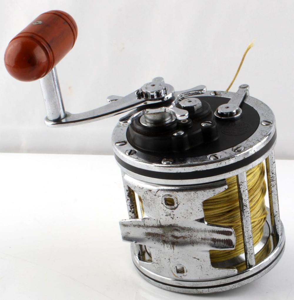 Vintage-looking fishing reel with chrome body, black spool, and gold line, shown on a white background.