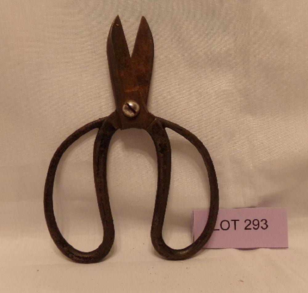 Brown metal scissors with pointed blades and ring handles, photographed on a light background.