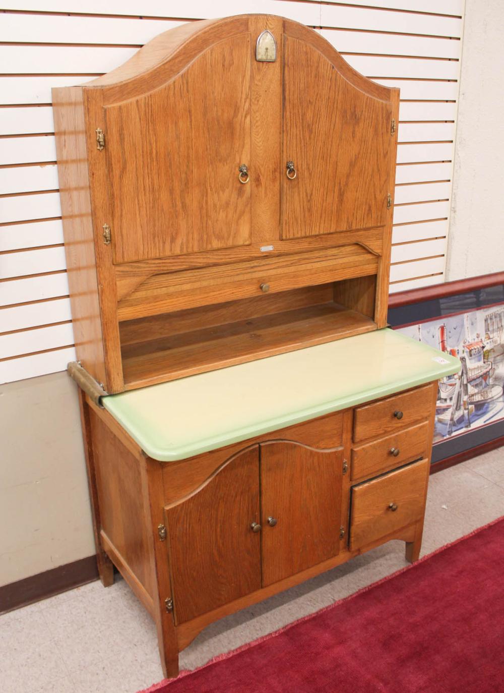 Vintage wooden kitchen cabinet with hinged upper doors and a countertop with light green backsplash panel.