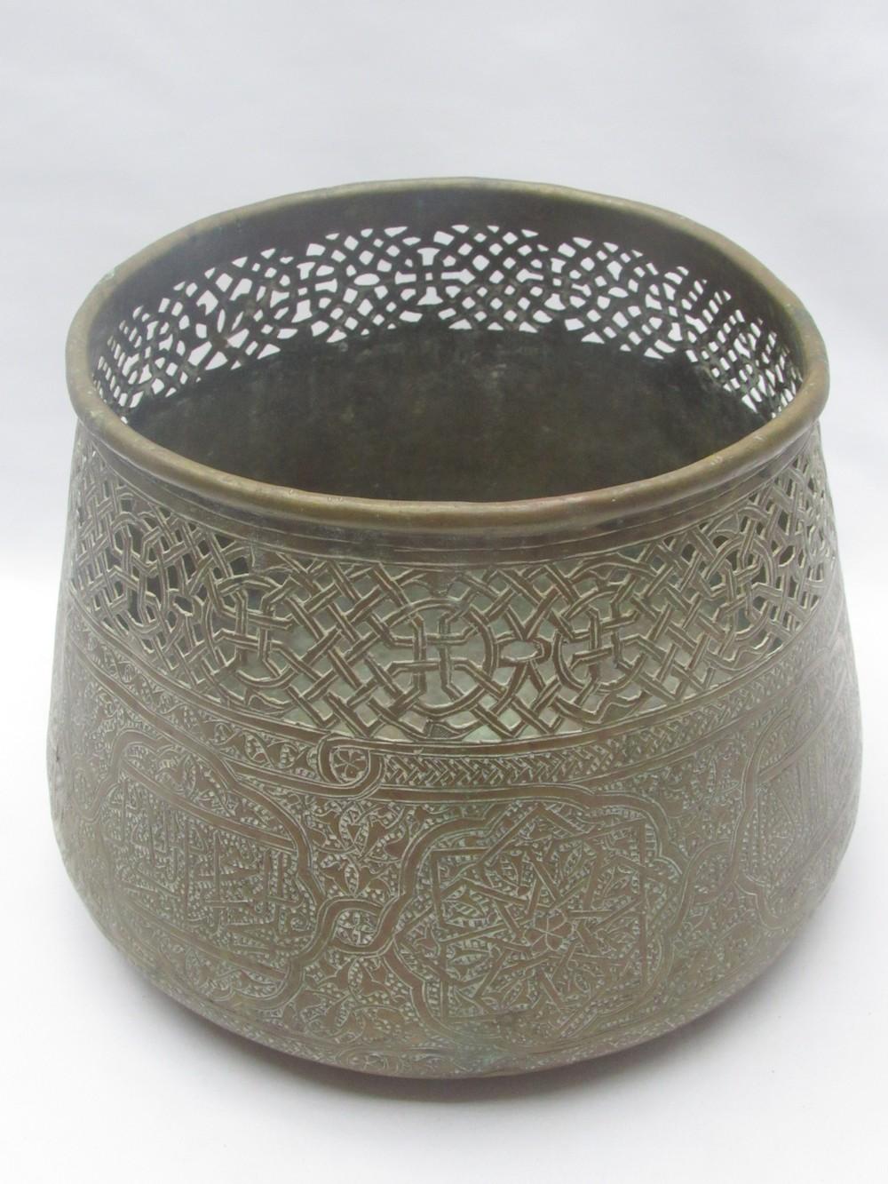Brass bowl-shaped vase with dark interior and raised geometric and arabesque pattern banding around the sides.