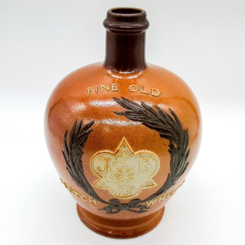 Brown ceramic whisky jug with a narrow neck and decorative metal-like leaf and crest design on the front.