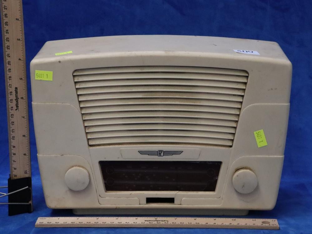 Front view of a vintage white bakelite-style radio with a horizontal grille speaker and a dark rectangular dial window.