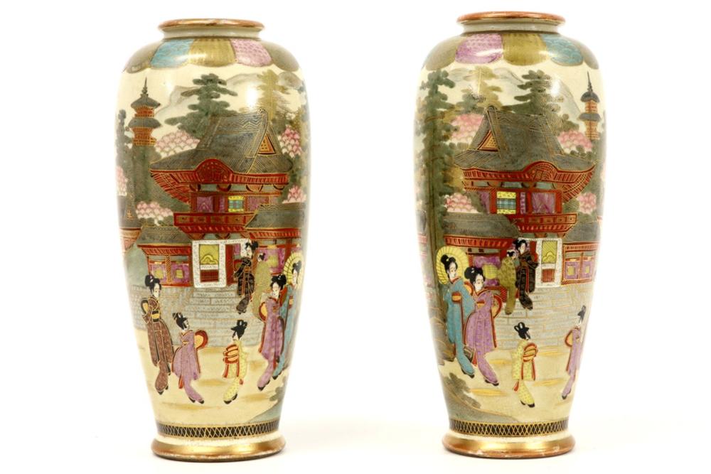 Pair of Japanese-style ceramic vases with colorful painted figures, pagoda buildings, and trees against a cream background.