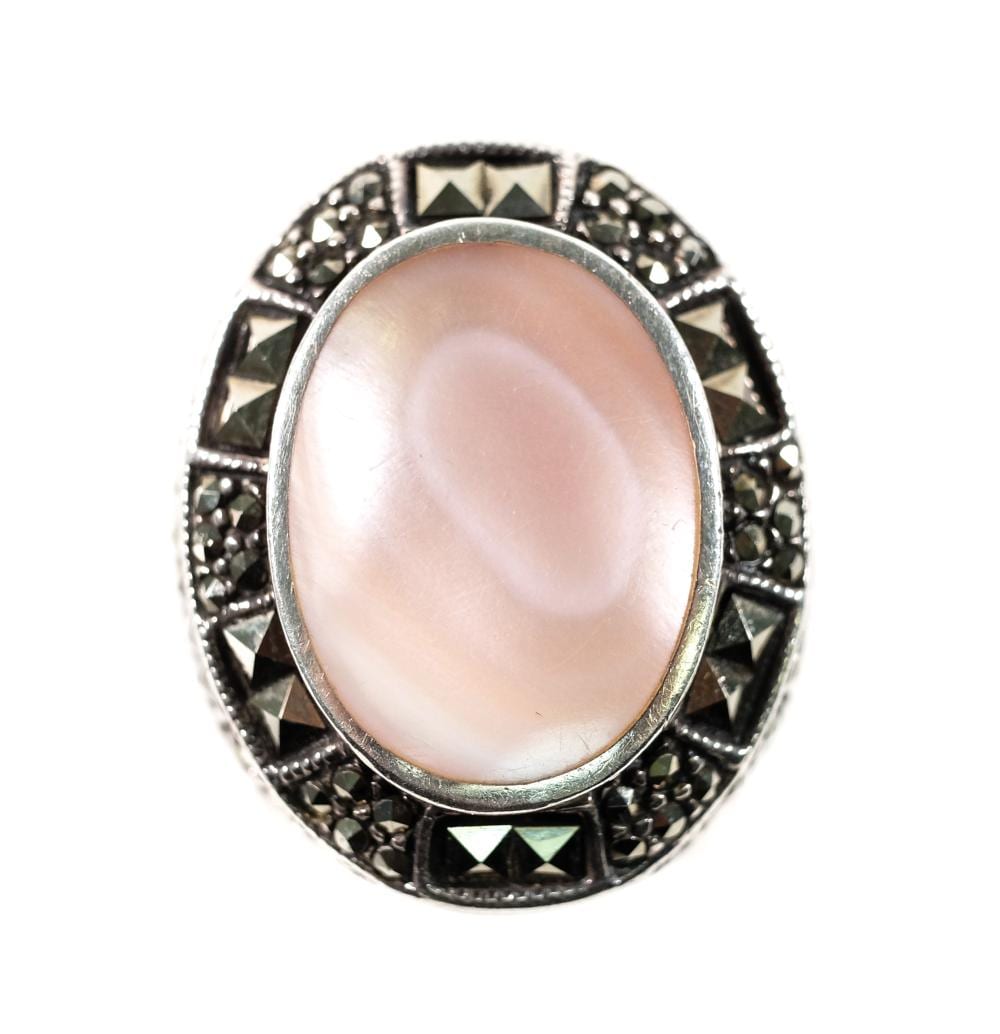 Oval pink cabochon gemstone set in a silver-toned ring with black and gray filigree-style accents.