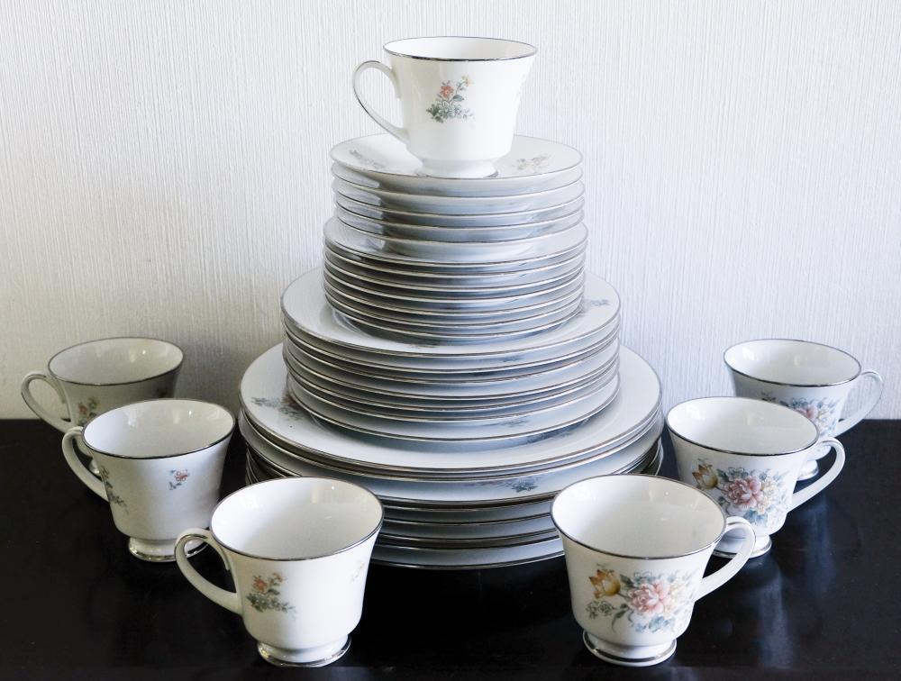 Stack of white porcelain cups and saucers with blue-gray striped pattern and small floral designs, plus several individual teacups.