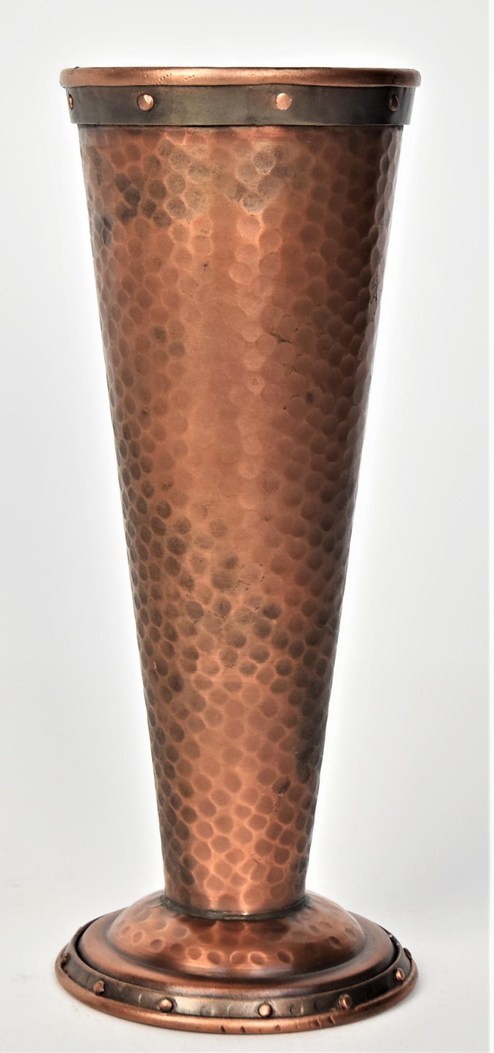 Copper-toned hammered vase with a dark banded top rim and circular base ring, shown upright against a light background.