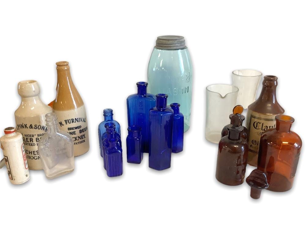 Lot of vintage glass bottles 8 cobalt blue, 3 Amber, and 1 clear . Two glass measuring containers. Three stoneware beer bottles and a Schlichte bottle. Large Red Mason jars. sold by Apple Tree Auction Center, lot 1559 — auction record photograph
