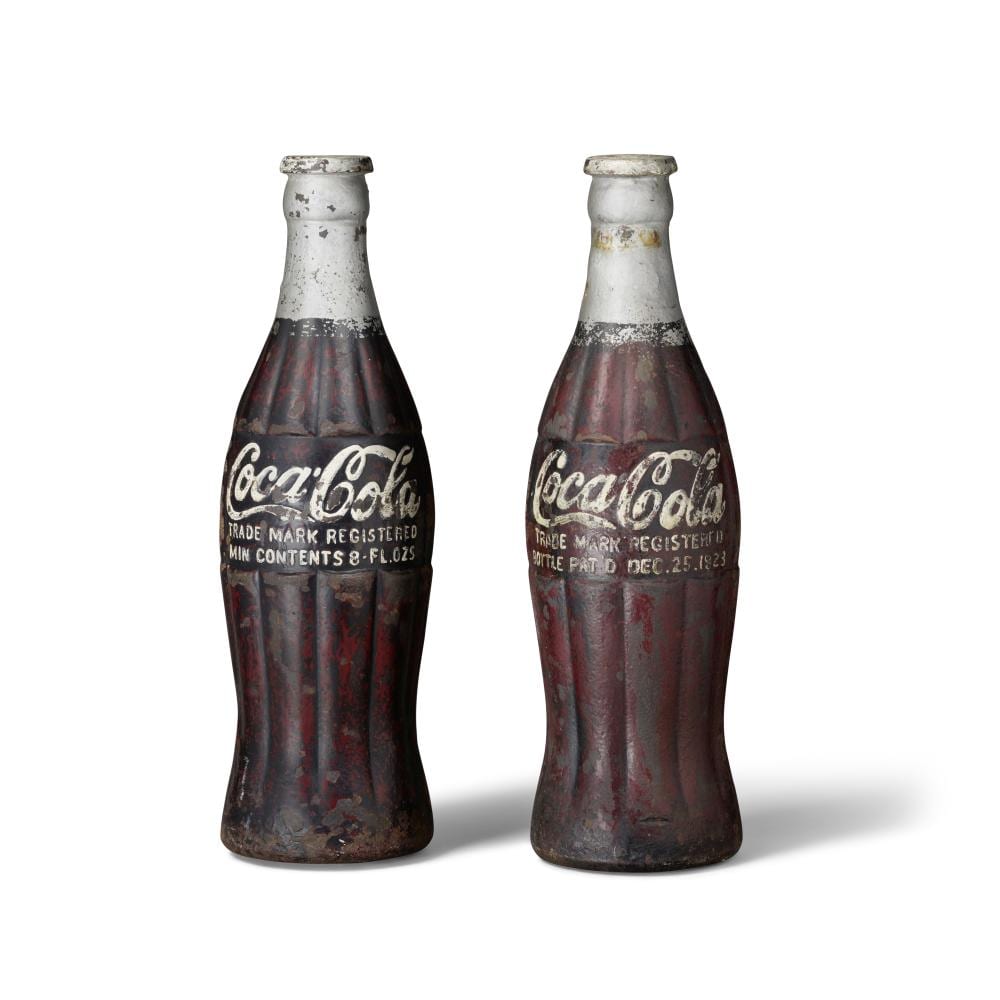 A RARE COMPANION PAIR OF PAINTED CAST IRON COCA-COLA BOTTLE SCULPTURES circa 1923height 20in (51cm) sold by Bonhams, lot 18 — auction record photograph
