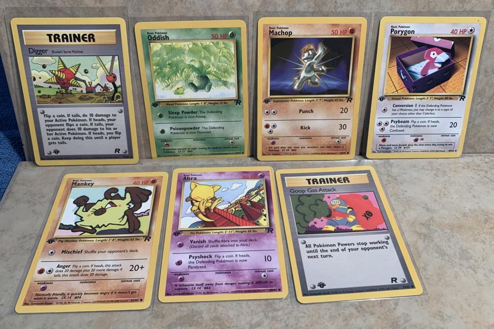 Six Pokemon trading cards arranged in two rows, featuring Trainer, Odish, Machop, Porygon, Mankey, Abra, and a card with the word “GOOP” near the bottom.
