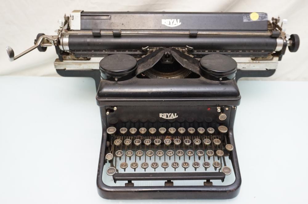 Black Royal typewriter with metal keys and a ribbon spool viewed from the front.