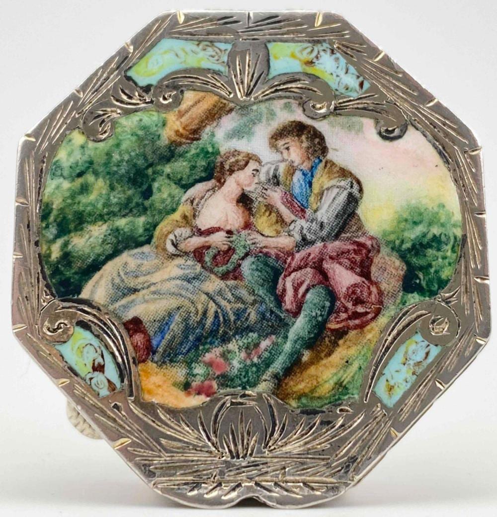 Silver-tone pill box with an enamel top showing two figures in a pastoral scene with greenery and trees.