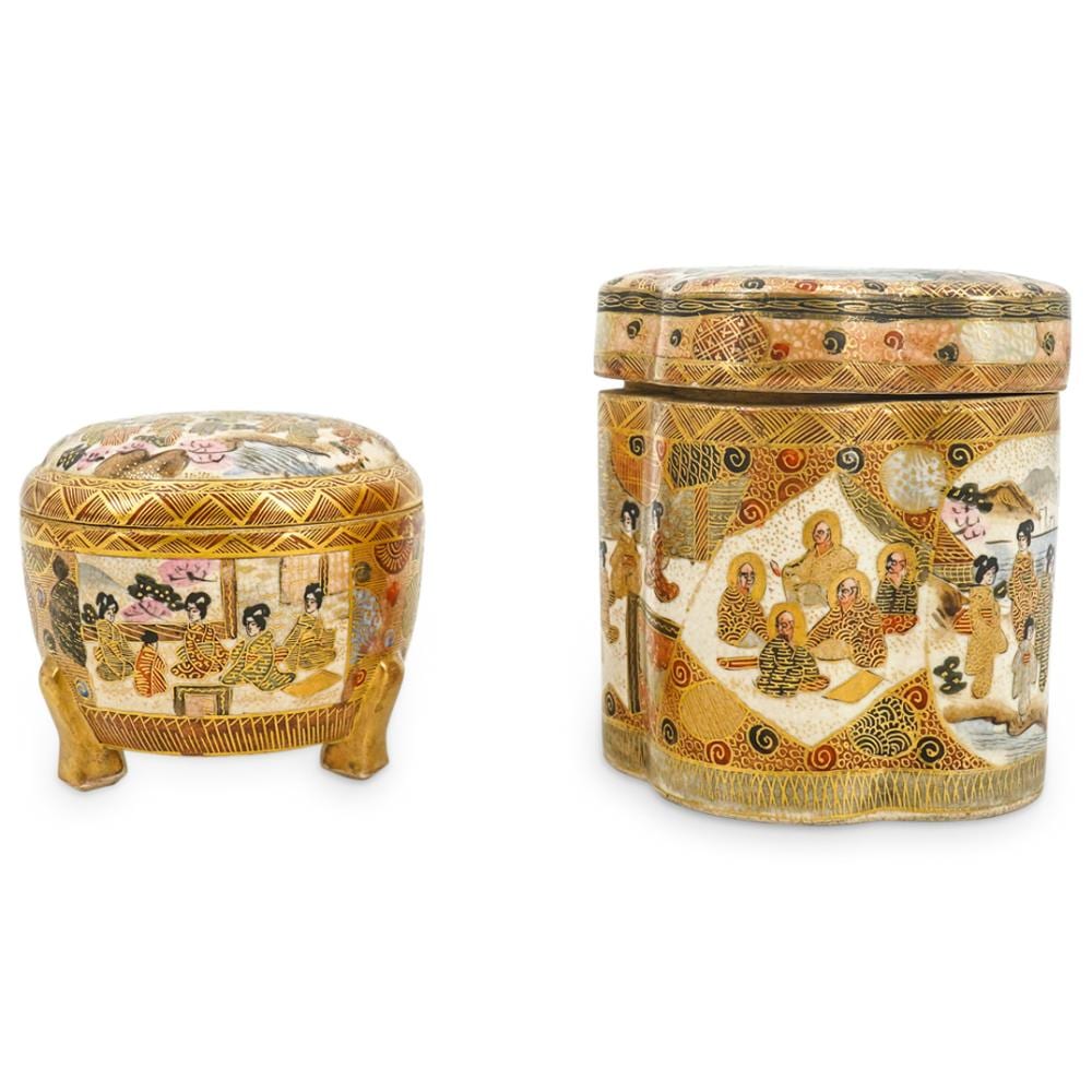 Two decorative porcelain lidded jars with painted scenes of figures and animals, each with four short legs or feet and gold accents.