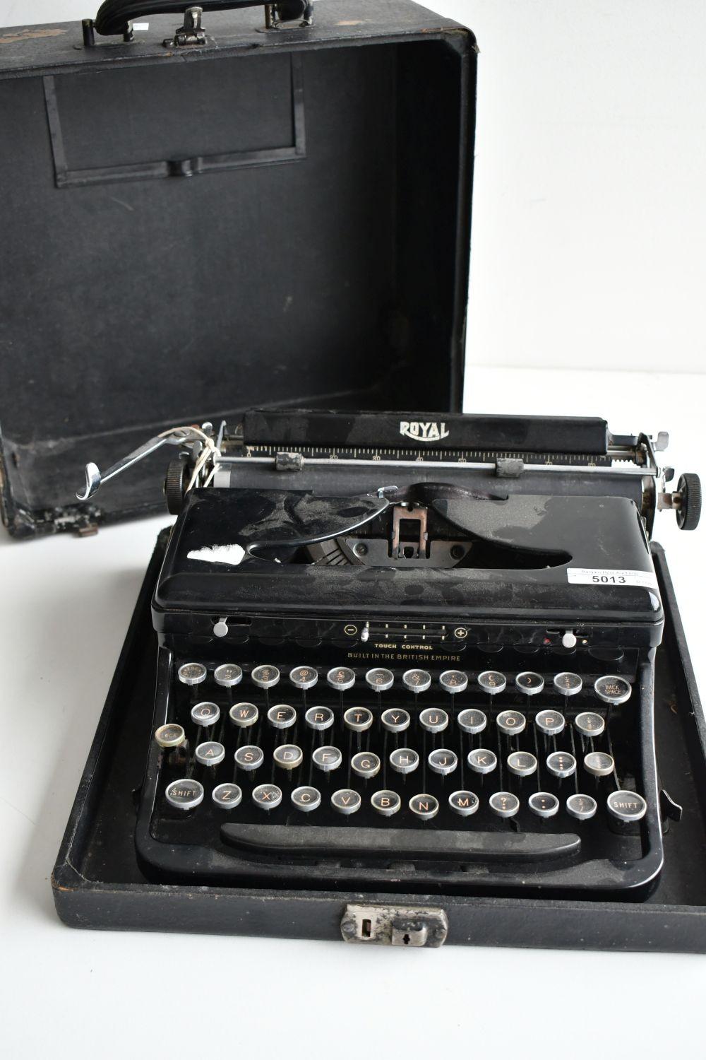 Black Royal portable typewriter with a keyboard of round keys, shown with its case open behind it.