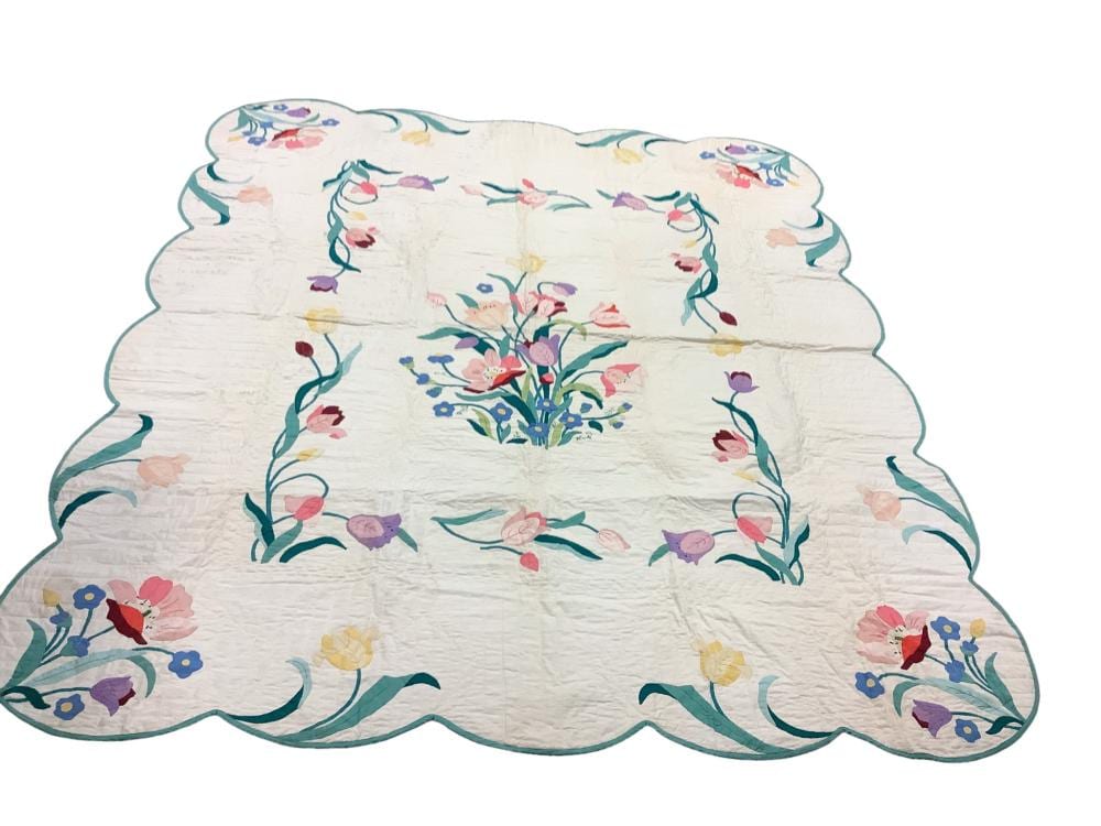 White quilt with floral applique and printed-style bouquets in pink, blue, yellow, and purple.