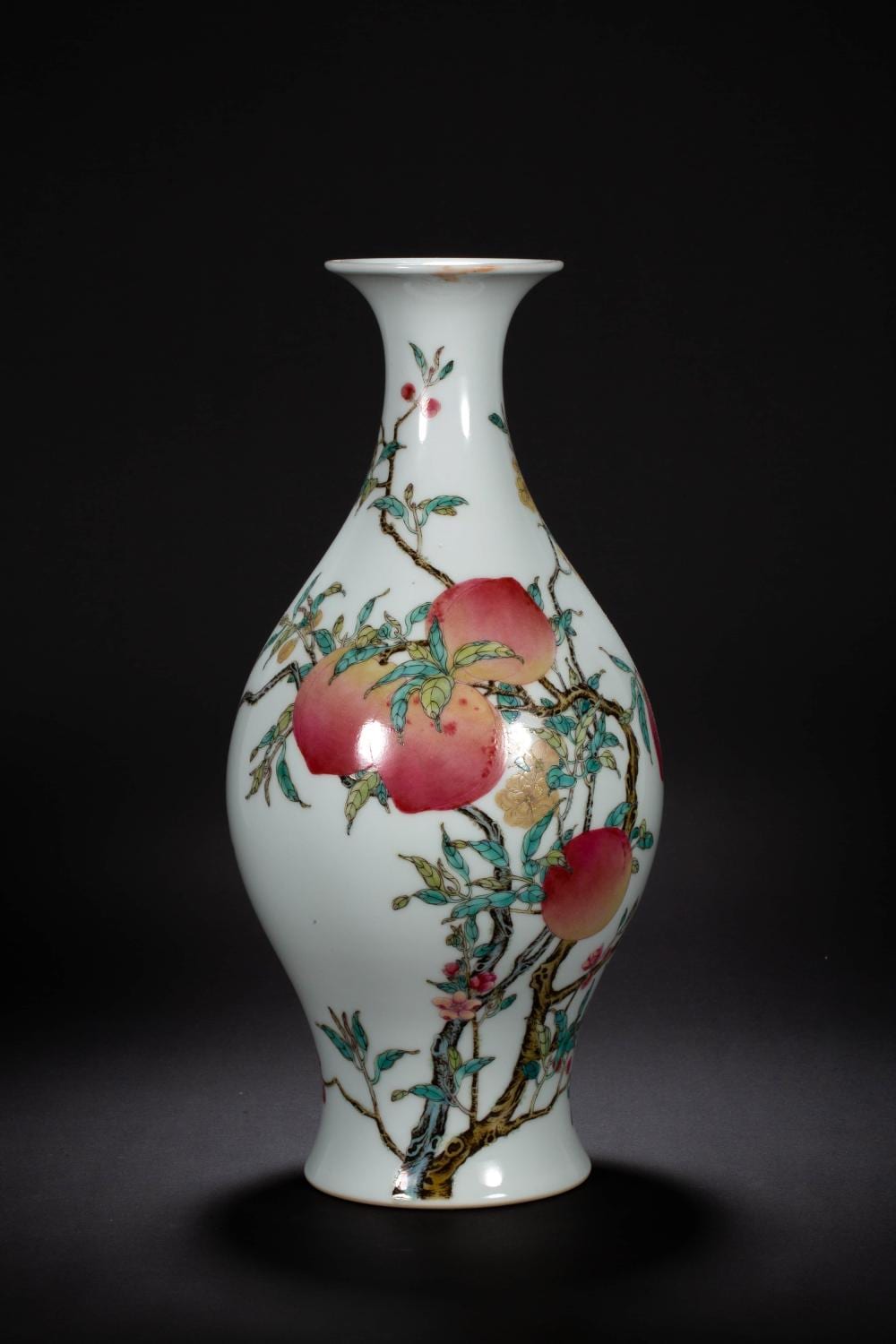 Porcelain vase with a narrow neck and flared rim, decorated with peach blossoms and green leaves in underglaze colors and gold accents.