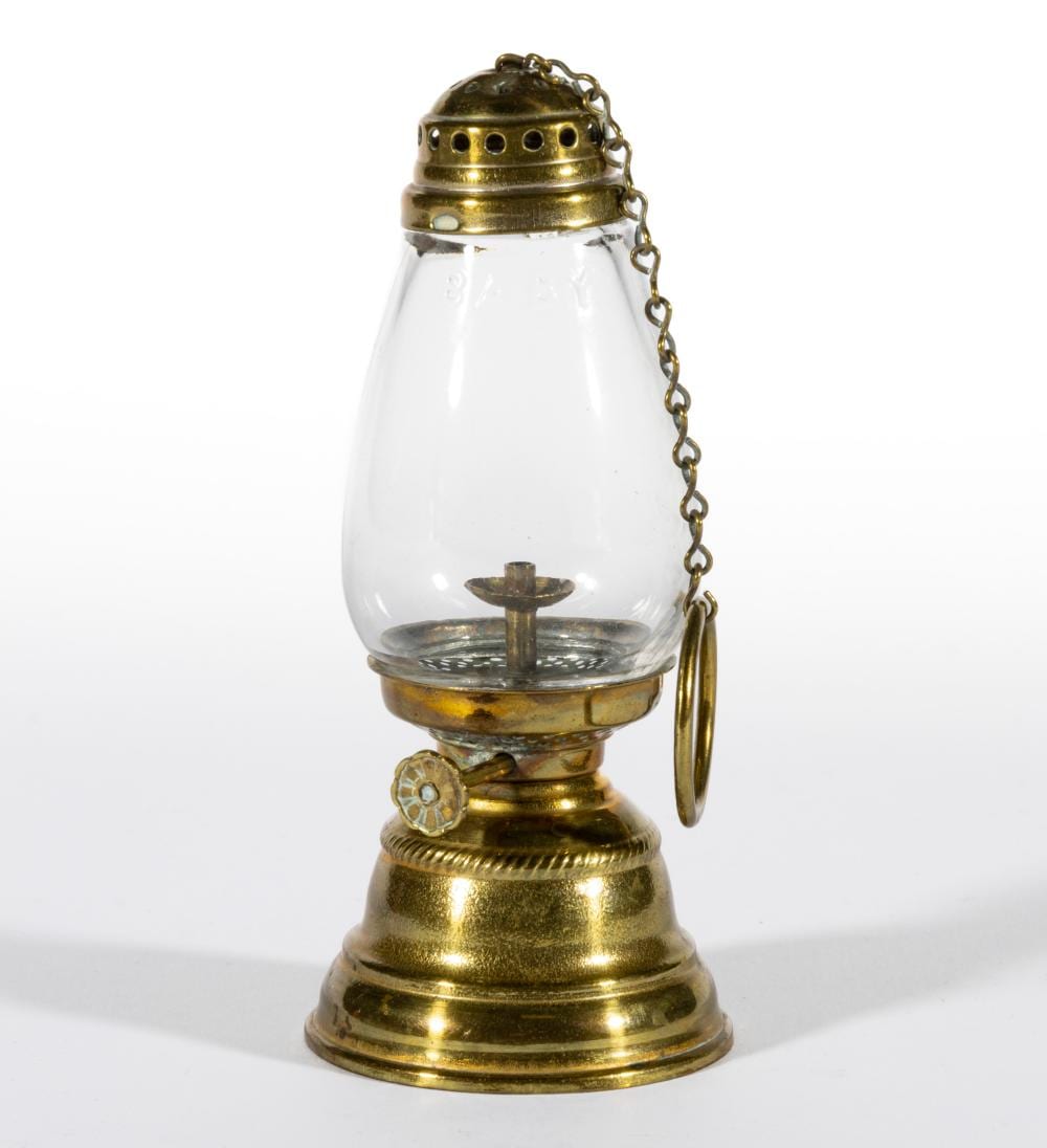 Small brass miniature lantern with clear glass reservoir and a chain handle, photographed on a white background.