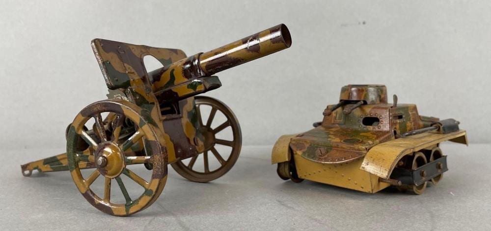 Two vintage tin lithography toy military vehicles: a cannon cart and a tracked tank with painted camouflage details.
