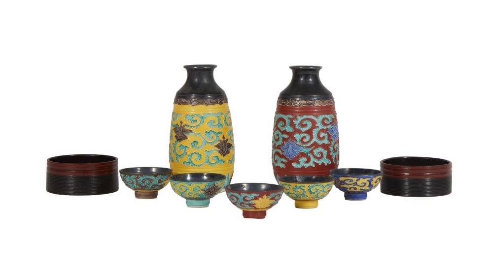 Nine-piece Japanese ceramic sake set with two blue-and-yellow decorated sake jugs, five small cups, and two black lacquer coasters