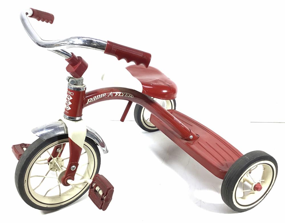 Red vintage-style three-wheeled Radio Flyer tricycle toy with chrome handlebars and front basket, shown on a white background.