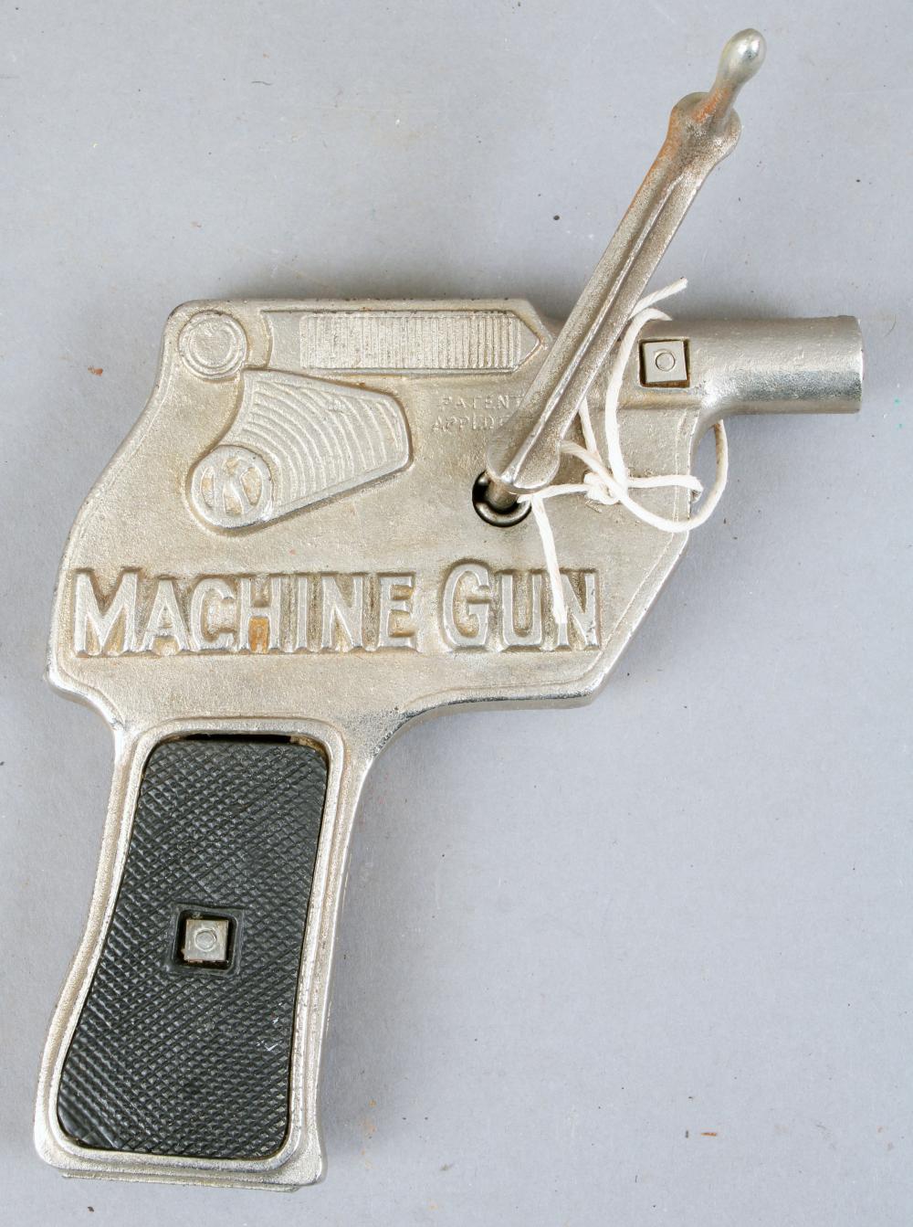 Cast metal toy cap pistol with a black textured grip and a crank handle, shown against a light background.