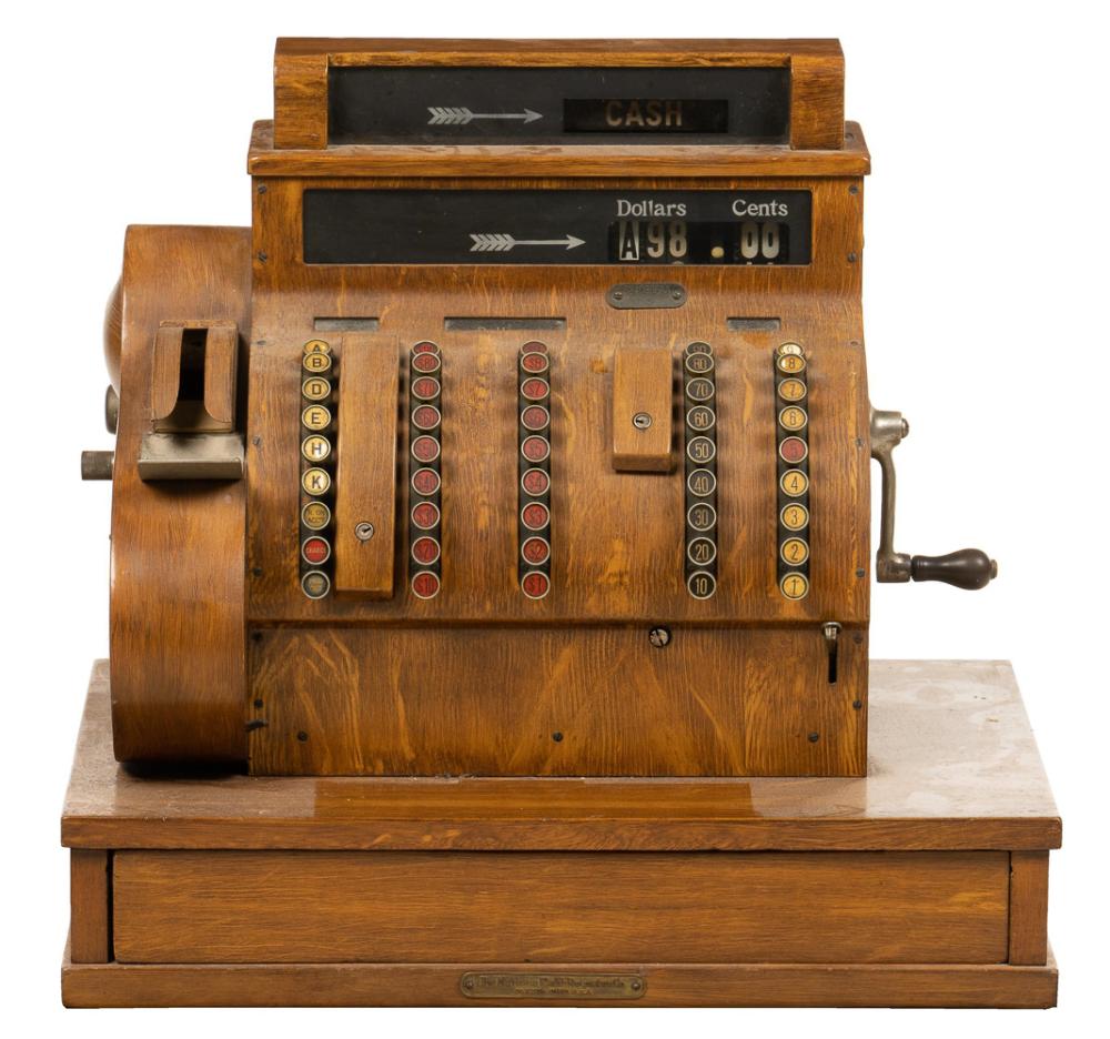 Vintage wooden cash register with a cash display, coin and bill counting dials, and a side crank handle.