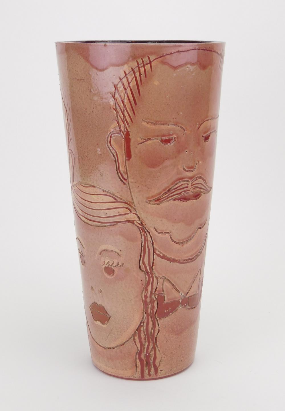 Tall pink ceramic vase with hand-drawn red and dark lines and face-like figures around the sides.