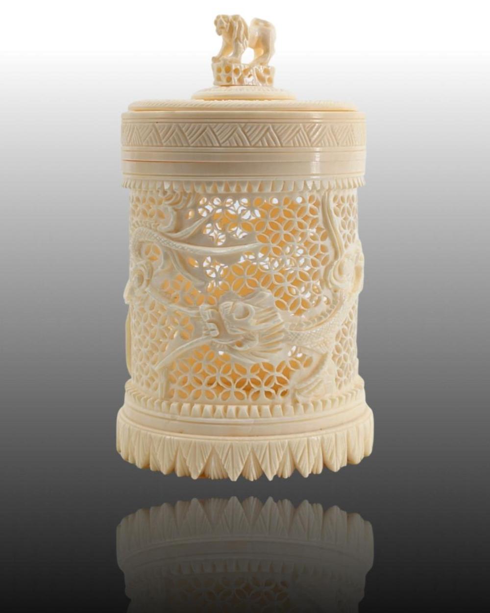 Carved ivory-colored cylindrical toothpick holder with a lid and dragon finial, decorated with floral and animal relief panels.