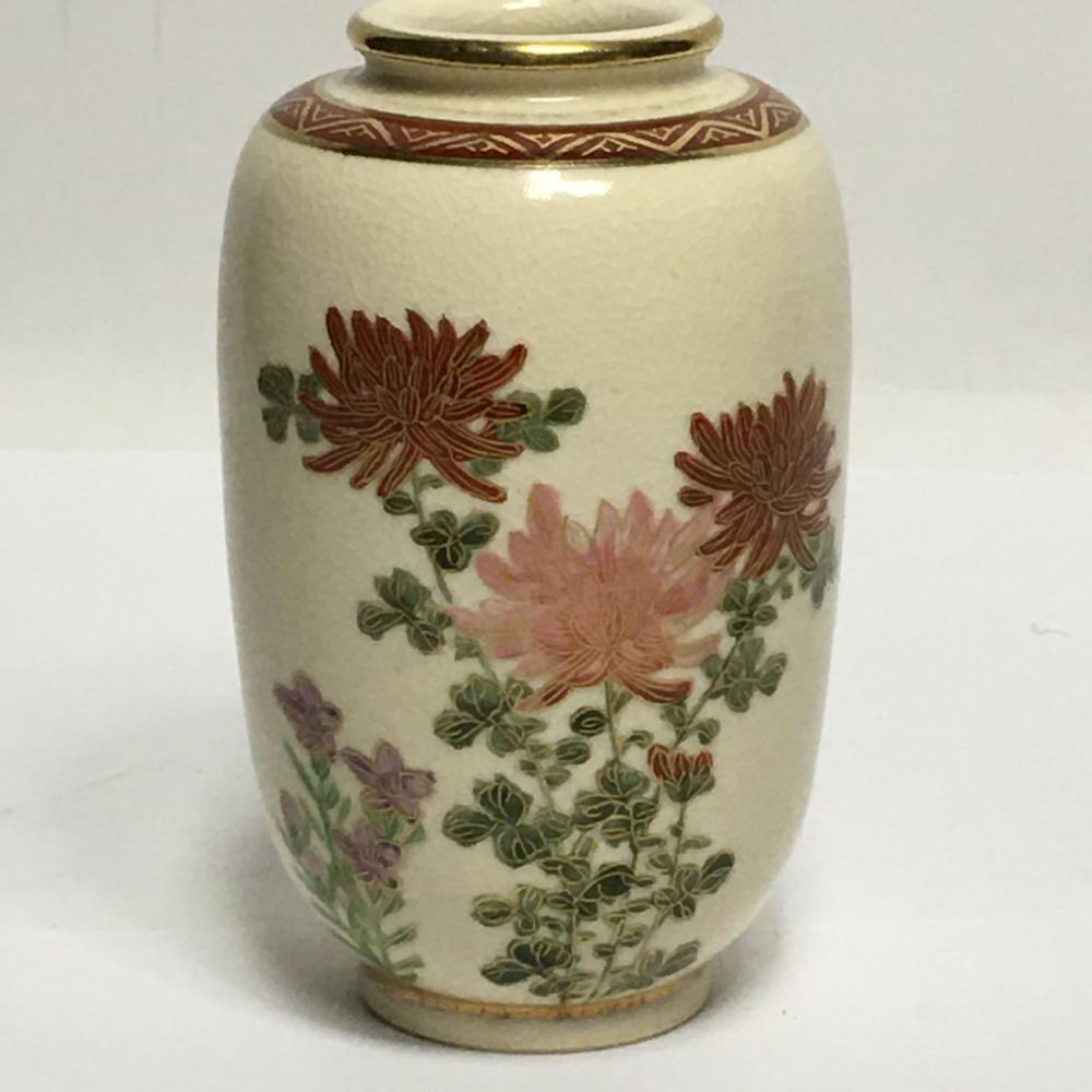 Porcelain vase with gold rim and painted flowers in red, pink, green, and purple, on a white background.